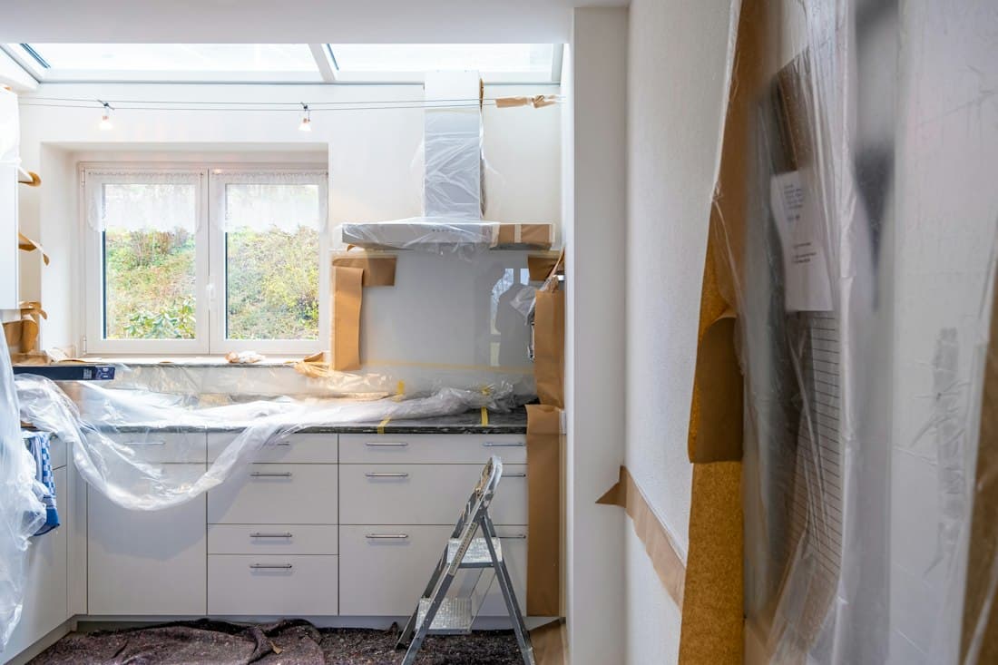 A kitchen covered in protective sheeting during renovation